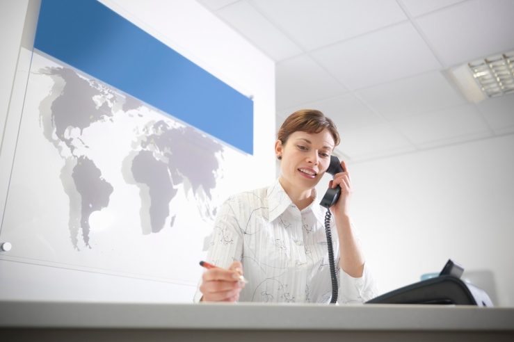 Dental receptionist taking telephone call at reception desk